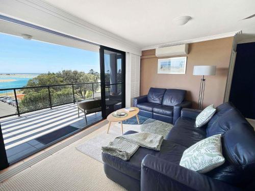 a living room with a couch and a balcony at Modern Apartment in the Heart of Cotton Tree in Maroochydore