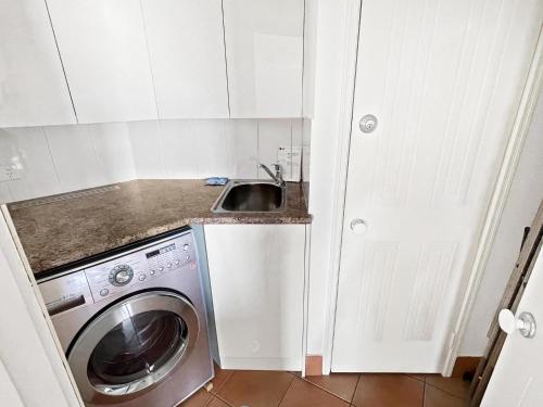 a small kitchen with a sink and a washing machine at Modern Apartment in the Heart of Cotton Tree in Maroochydore