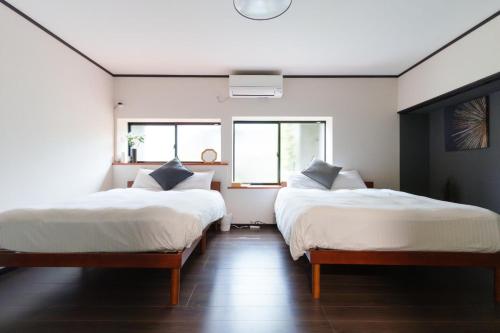 zwei Betten in einem Zimmer mit zwei Fenstern in der Unterkunft Habitacion Cottage Jin in Azagawa