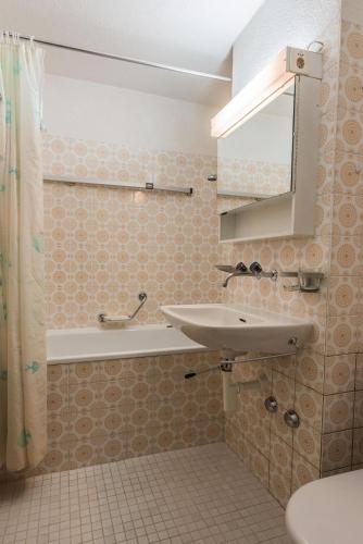 a bathroom with a sink and a bath tub at Residenza Tga Clo Apartment 09 in Savognin
