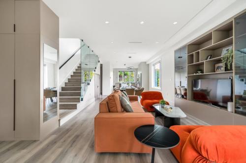 a living room with an orange couch and a staircase at Charming and Modern Retreat in Vancouver Trendy 42nd Avenue Neighbourhood in Vancouver