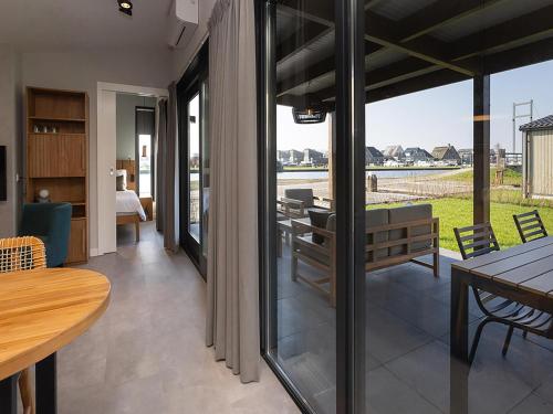 a room with a dining table and a room with a view at Docklodge at Frisian Lakes with Private Mooring in Delfstrahuizen