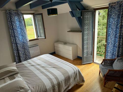 une chambre avec un lit et une grande fenêtre dans l'établissement Moulin du pont rouge, à Soudaine-Lavinadière