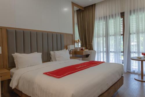 a bedroom with a large bed with a red blanket on it at Villa Oasis in Luang Prabang