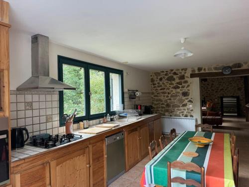 une cuisine avec une table et une cuisinière four supérieur dans l'établissement Moulin du pont rouge, à Soudaine-Lavinadière