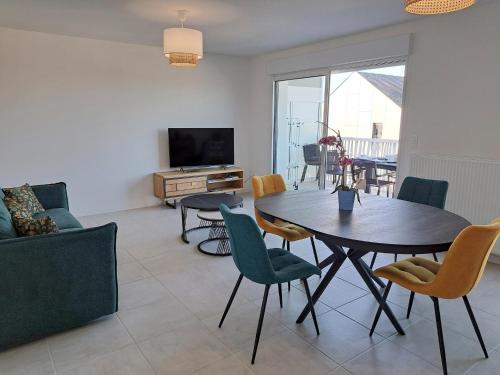 a living room with a table and chairs and a television at Apartment in Finistère with Free E-Bike in Plouarzel