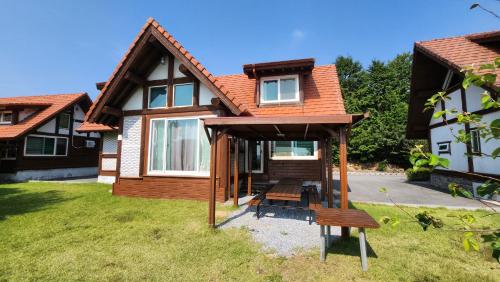 a house with a porch with a bench in the yard at 보성녹차리조트 in Boseong