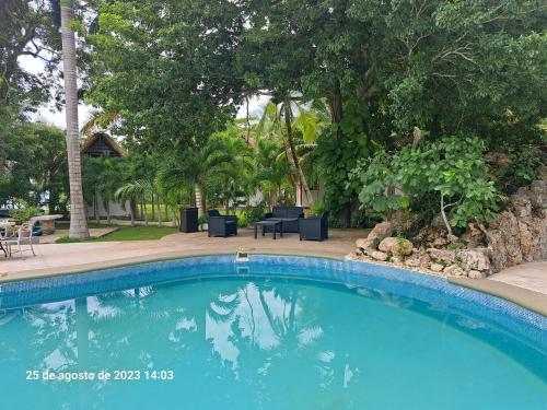 a swimming pool in front of a yard with trees at Xanthus Hotel in Huay Pix