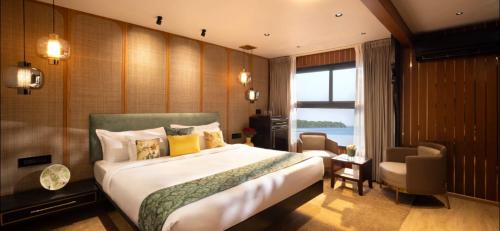 a bedroom with a bed and a chair and a window at Royal Houseboats in Alleppey