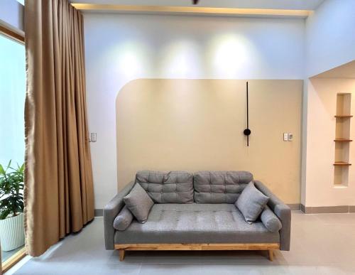 a couch in a living room with a clock on the wall at Central, Minimalist and Cozy - Gau's House in Da Nang