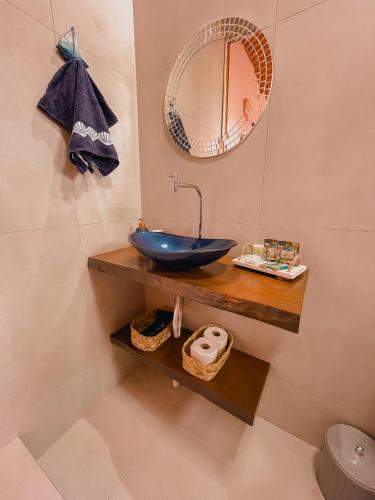 a bathroom with a blue sink and a mirror at Shangri La Casas e Studios in Praia do Rosa