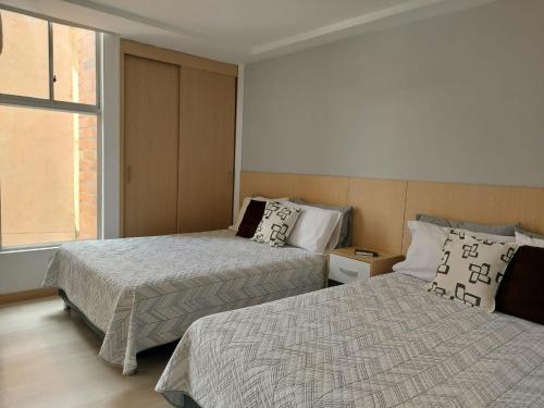 a bedroom with two beds and a window at San Peter Family Suites in Medellín