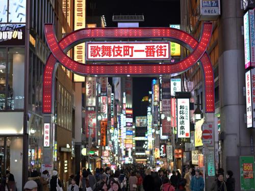 a busy city street at night with neon signs at Shinjuku Prince Hotel in Tokyo