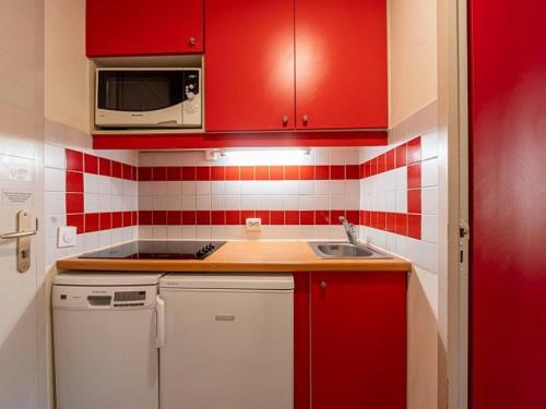 - une cuisine rouge avec évier et four micro-ondes dans l'établissement Studio ensoleillé à La Plagne avec balcon et parking - FR-1-351-249, à La Plagne Tarentaise