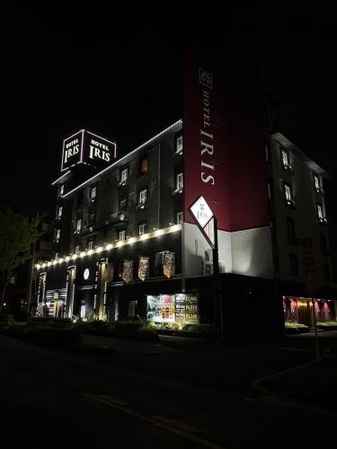 a tall building with lights on it at night at Hotel IRIS -アイリス- in Osaka