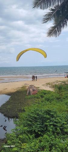 a paraglider flying over a beach with the ocean at Pousada Paraíso Beach in Santa Cruz Cabrália