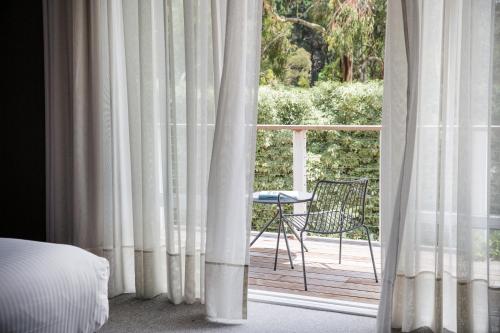 a bedroom with a view of a patio through curtains at Lancemore Lindenderry Red Hill in Red Hill