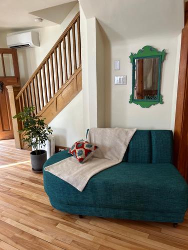 a green couch in a living room with a staircase at Retro-chic retreat in the heart of Wakefield in Wakefield