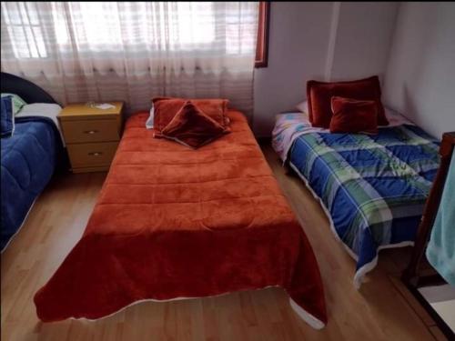 a bedroom with two beds and a large red blanket at Hostal ML LAS TRES B in El Cocuy