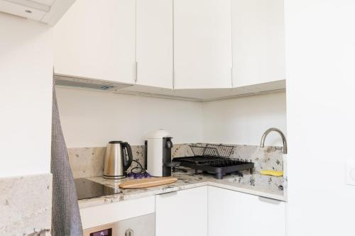 une cuisine blanche avec des armoires blanches et un évier dans l'établissement Nouveau studio au cœur de l'Opéra - Paris 1er, à Paris