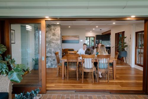 a group of people sitting at a dining room table at Executive Paradise High on Hill with Incredible Views, Firepit & Games Perfect for groups of Family and Friends in Balmoral Ridge
