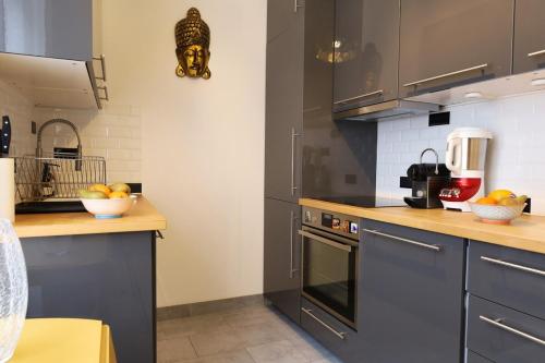 - une cuisine avec des placards gris et un bol de fruits sur le comptoir dans l'établissement St Georges proche Opéra et la Basilique sacrée, à Paris