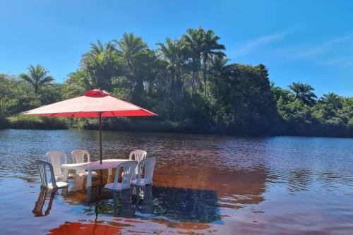 a table and chairs in the water with an umbrella at Espaço Bem Bom in Andaraí