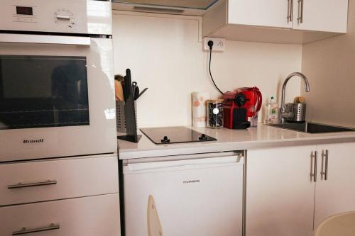 une petite cuisine avec des armoires blanches et un appareil rouge dans l'établissement Studio confortable et moderne au cœur de Paris, à Paris