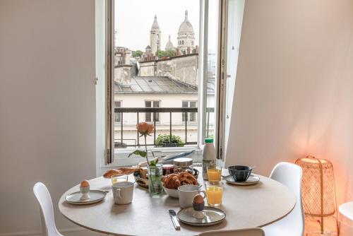 - une table avec de la nourriture et une vue sur la ville dans l'établissement Une vue magnifique sur le Sacré Cœur., à Paris