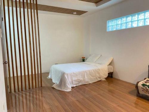 a white bedroom with a bed and a window at RHM homestay in Naga