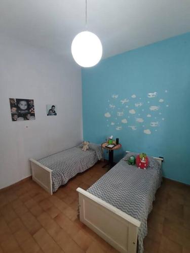 a room with two beds and a blue wall at Casa a pocas cuadras del centro in Zárate