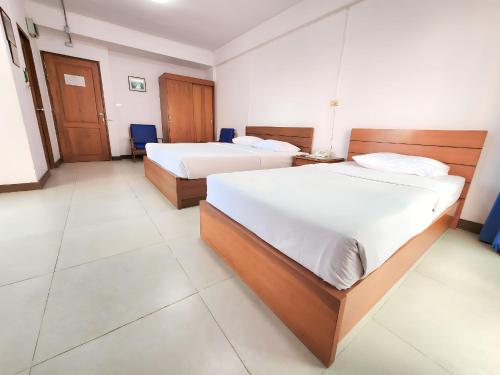 two beds in a hotel room with white walls at Siam Palace Hotel in Bangkok