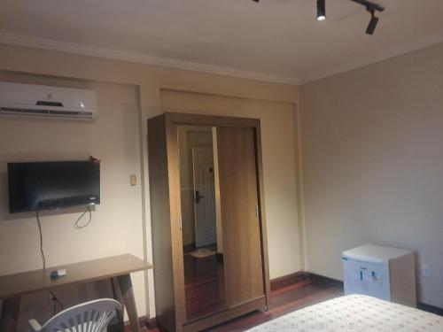 a bedroom with a wooden door and a television at Casa Rosa Suítes 5 min de caminhada da PRAIA DA PONTA NGRA in Manaus