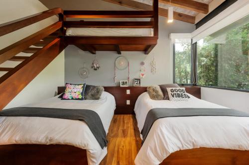 Dos camas en una habitación con suelo de madera y escaleras. en Casa Galo-Modern Retreat Overlooking Golf Course, en Valle de Bravo