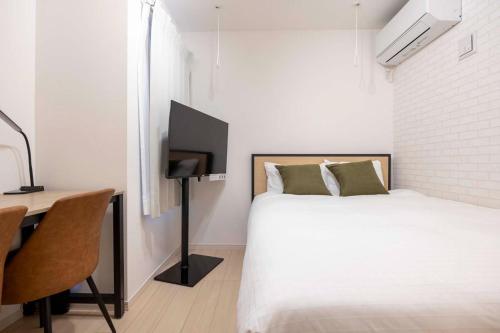 a bedroom with a bed and a desk with a television at Harbors Residence Yahiro in Tokyo