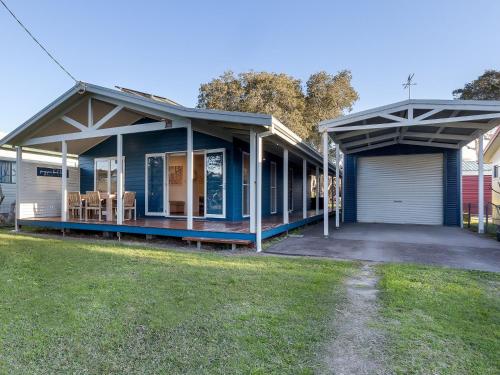 a blue house with a garage and a yard at Frangipani Hat Head in Hat Head