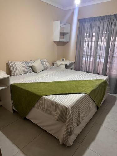 a bedroom with a large bed with a green blanket at Cebos oasis in Mataffin
