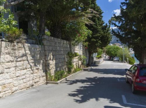 a car parked on a street next to a stone wall at Beachfront Apartments Andrijević in Brist
