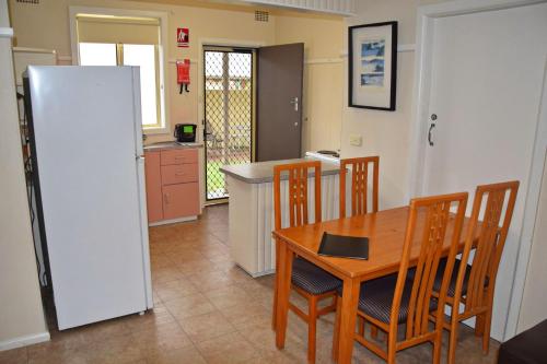 Una cocina con mesa y sillas y un refrigerador. en Clarkes Flat 1, en South West Rocks