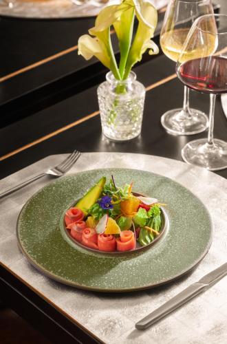 a plate of salad on a table with wine glasses at The Au Co Cruise - Managed by Bhaya Cruise in Ha Long