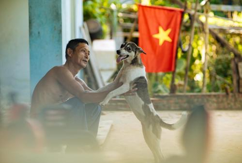 a man holding a dog in front of a flag at The Au Co Cruise - Managed by Bhaya Cruise in Ha Long