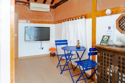 a room with a table and chairs and a tv at Beautiful Garden Fine Day House in Jeonju