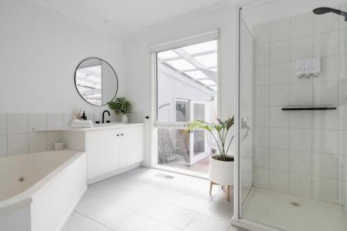 a white bathroom with a shower and a sink and a mirror at The Hideaway - Coastal Chic Living in Blairgowrie