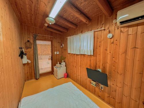 a bedroom with wooden walls and a bed in a room at Beautiful Garden Fine Day House in Jeonju