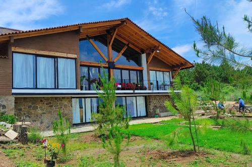 a house with large glass windows in a yard at Villa Alejandra Cabaña in Tapalpa
