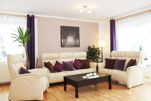 een woonkamer met een witte bank en paarse kussens bij Ferienhaus im Bleitz in Wrestedt