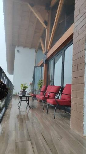 a row of red chairs sitting on a balcony at Villa Alejandra Cabaña in Tapalpa