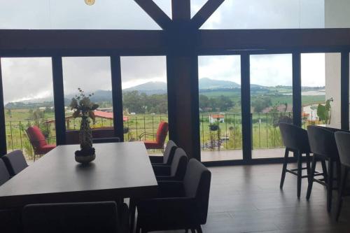 a dining room with a table and chairs and windows at Villa Alejandra Cabaña in Tapalpa