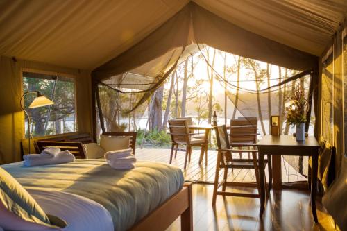 a bedroom with a tent with a table and chairs at Tanja Lagoon Camp in Tanja