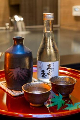 a red tray with a bottle and two bowls on it at すみや 青花 in Takayama